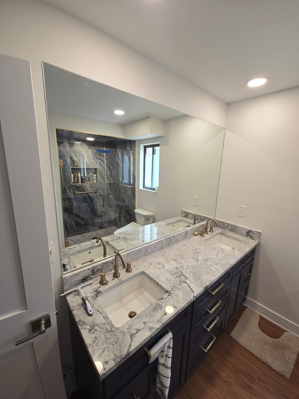Large frameless mirror over a marble double vanity
