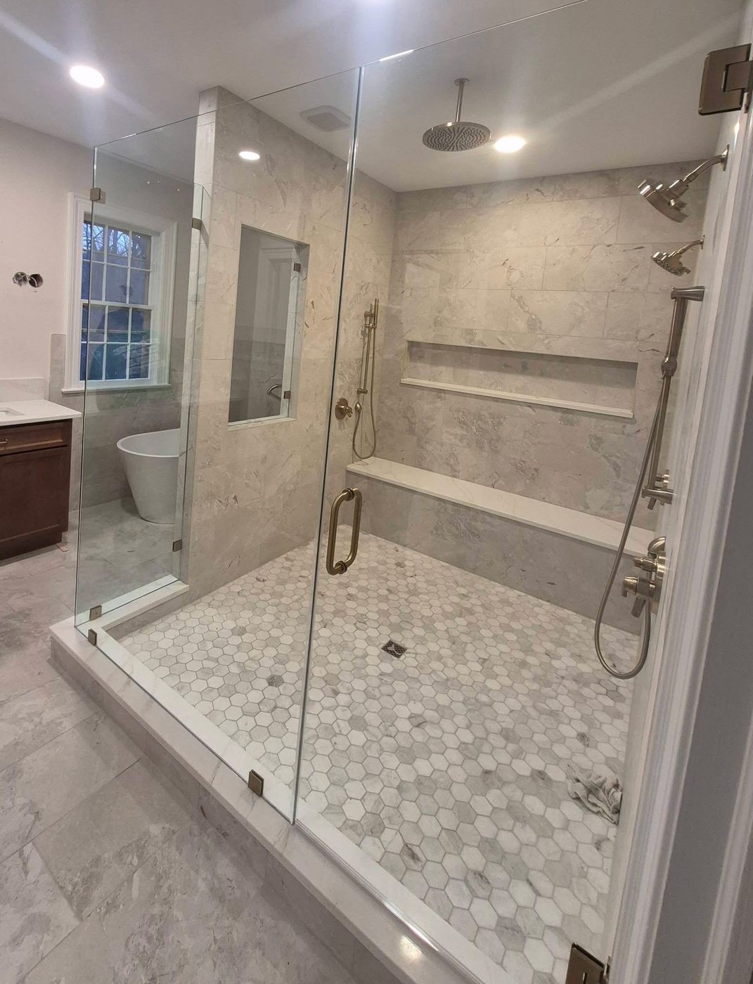 Frameless glass shower with marble walls and pebble floor