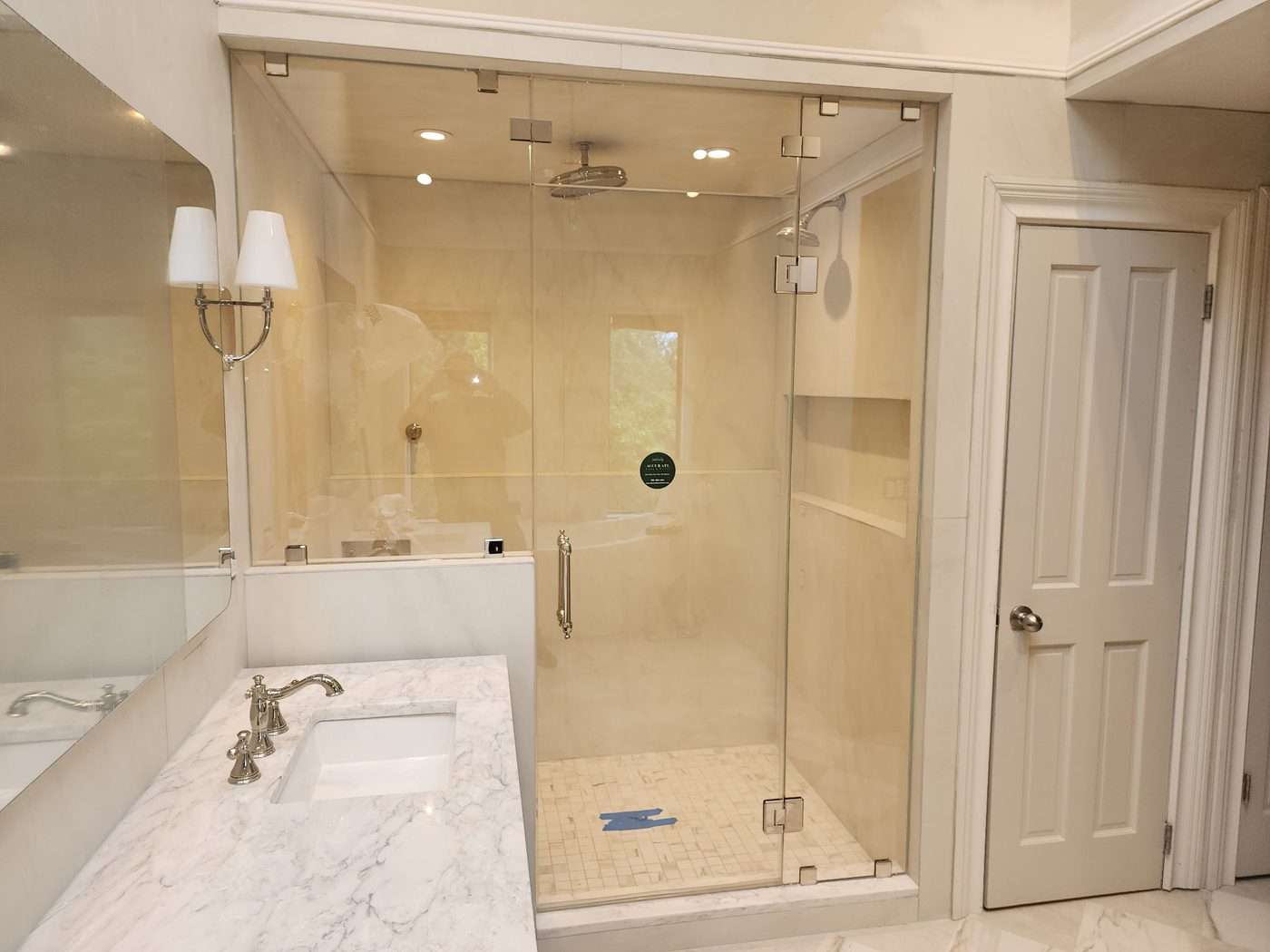 Frameless glass shower with marble walls and built-in bench
