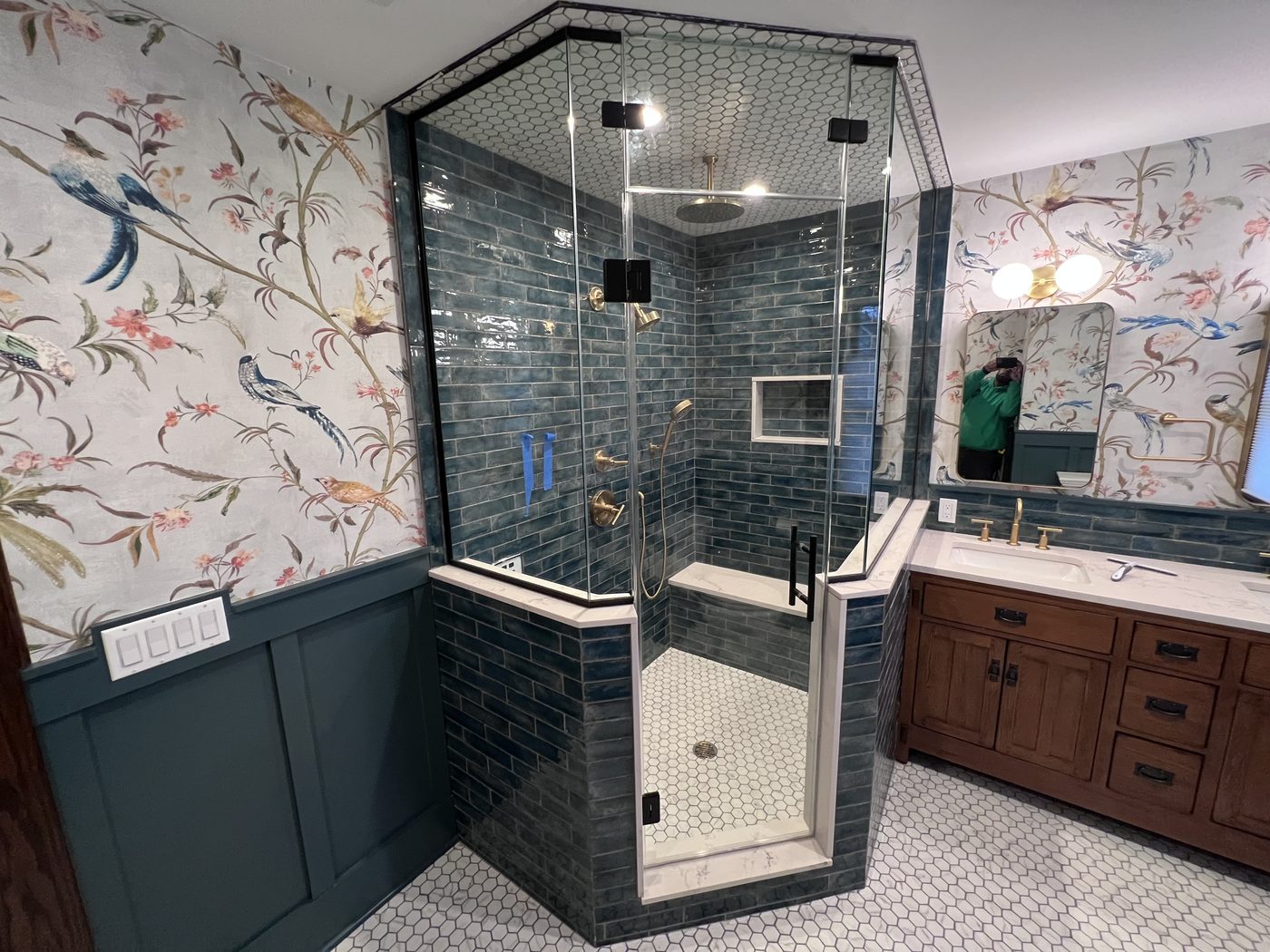 Black-framed corner shower beside a wallpapered vanity
