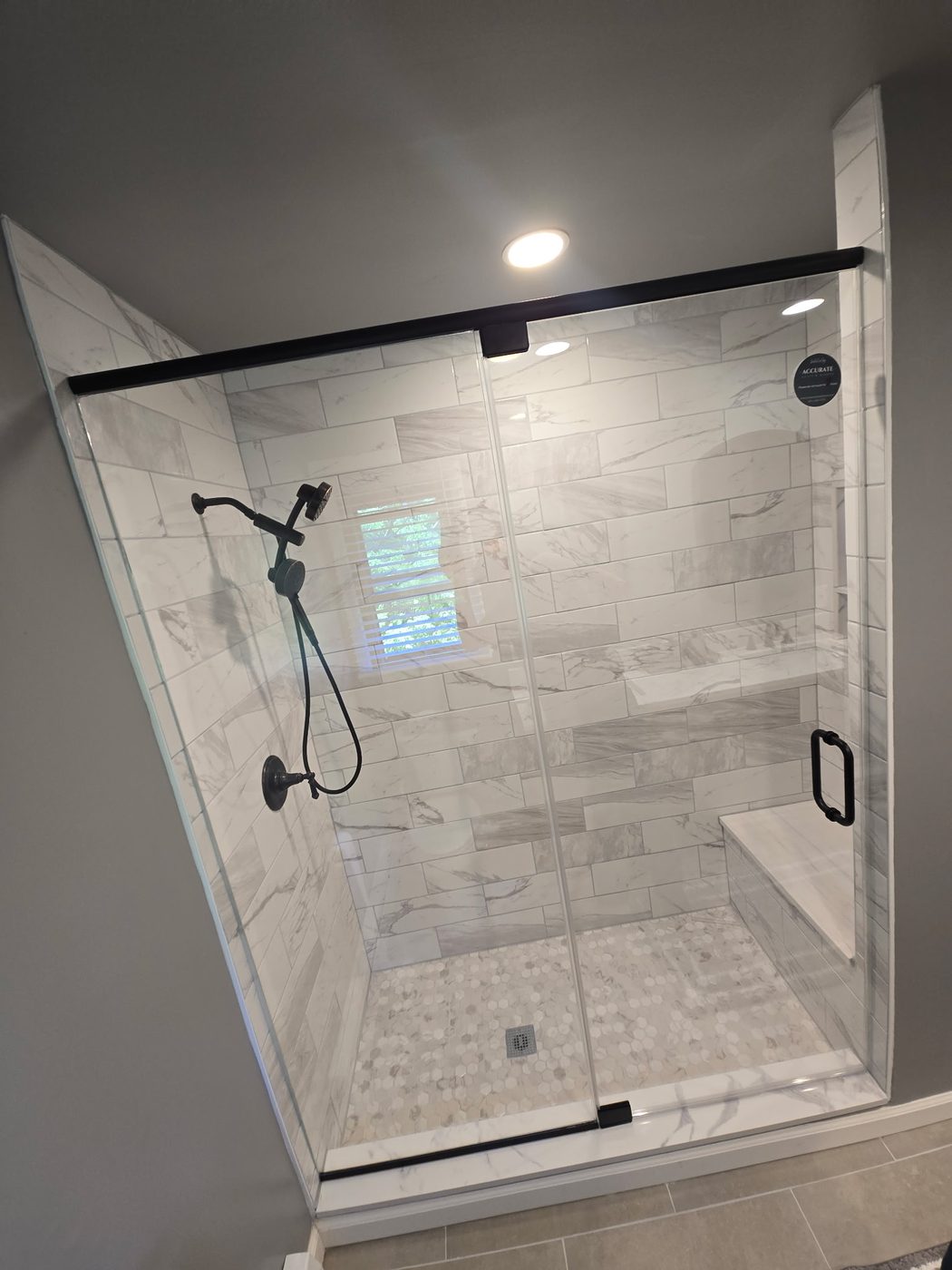 Frameless glass shower enclosure with black fixtures and bench