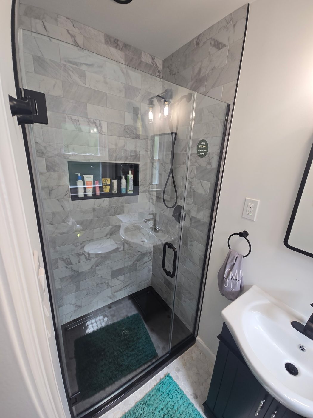 Walk-in glass shower with black frame and marble tile