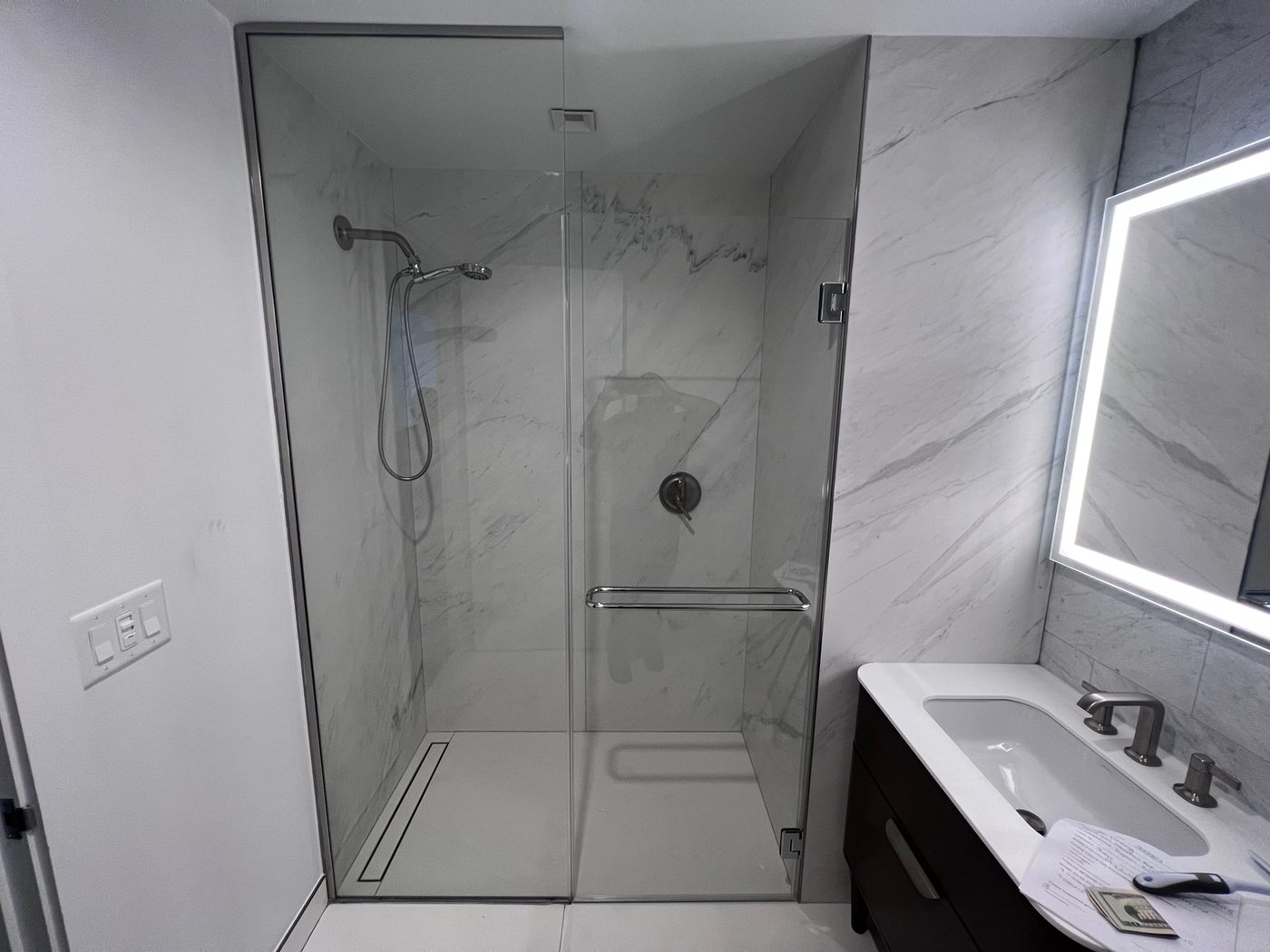 Frameless glass shower with light gray tile