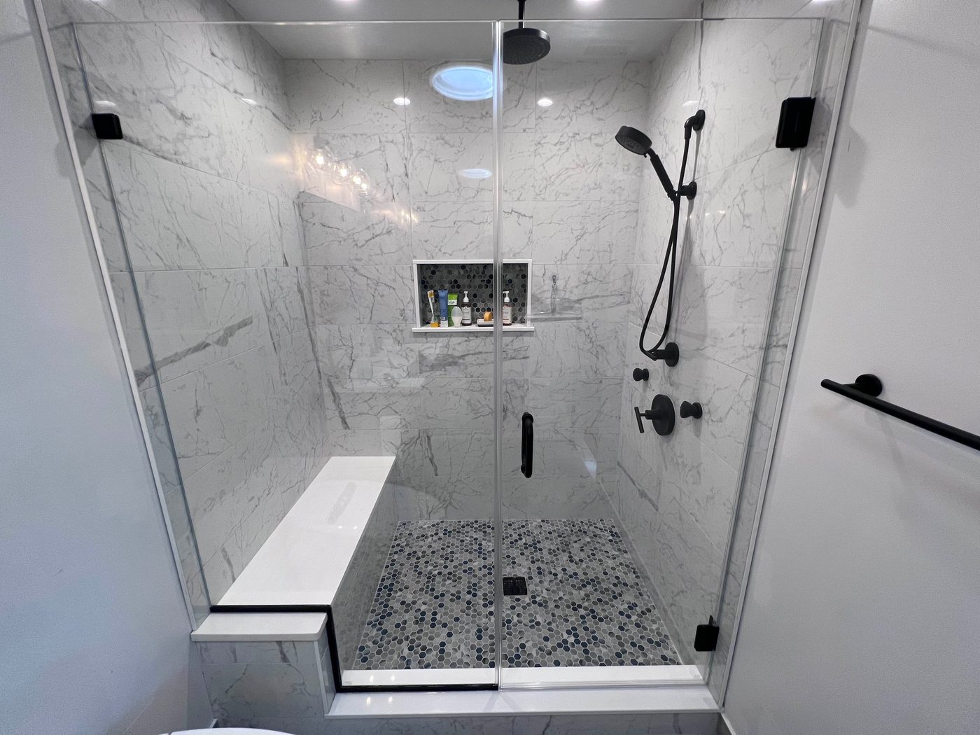 Frameless glass shower with marble and black hardware