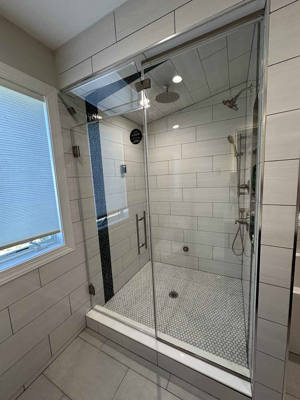 Large frameless glass shower with marble and a window
