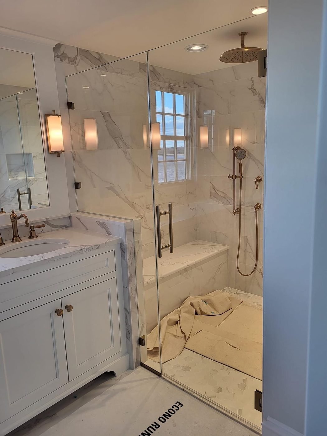 Frameless glass shower with white vanity and marble tile