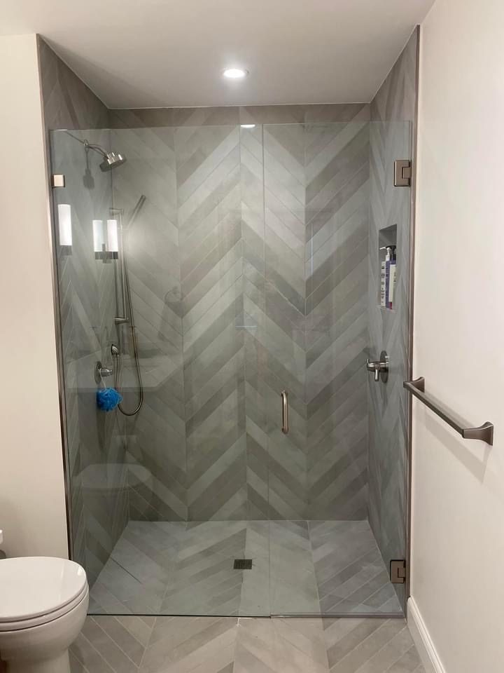 Frameless glass shower with herringbone marble tile