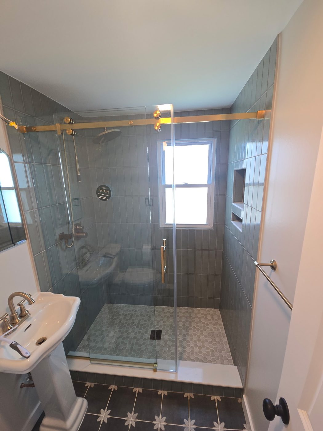 Frameless glass shower with brass fixtures and window