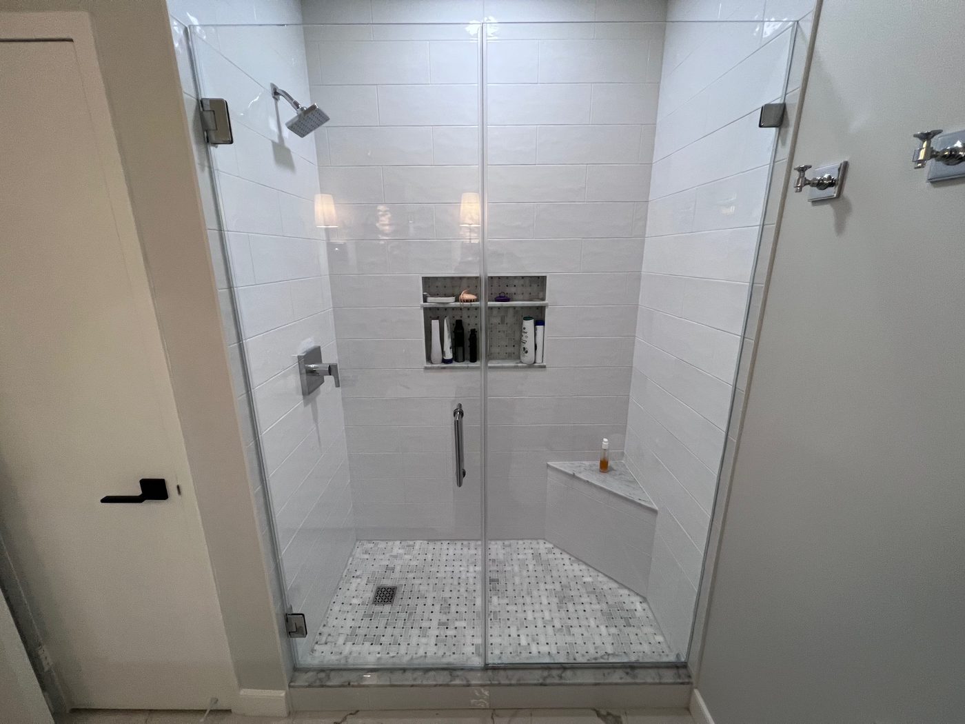 Frameless glass shower with a tiled bench and niche