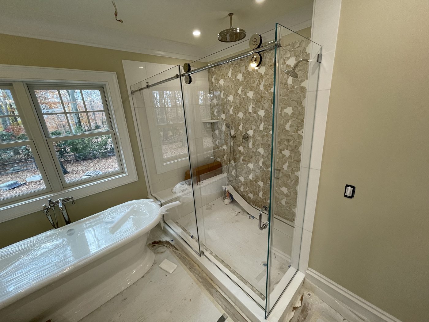 Frameless glass shower beside a window with patterned floor