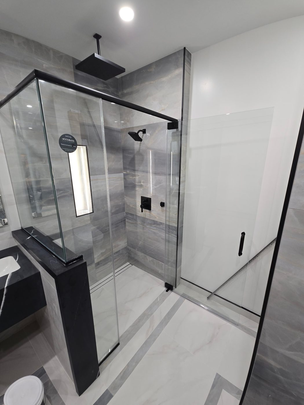 Black-framed glass shower with marble and bench